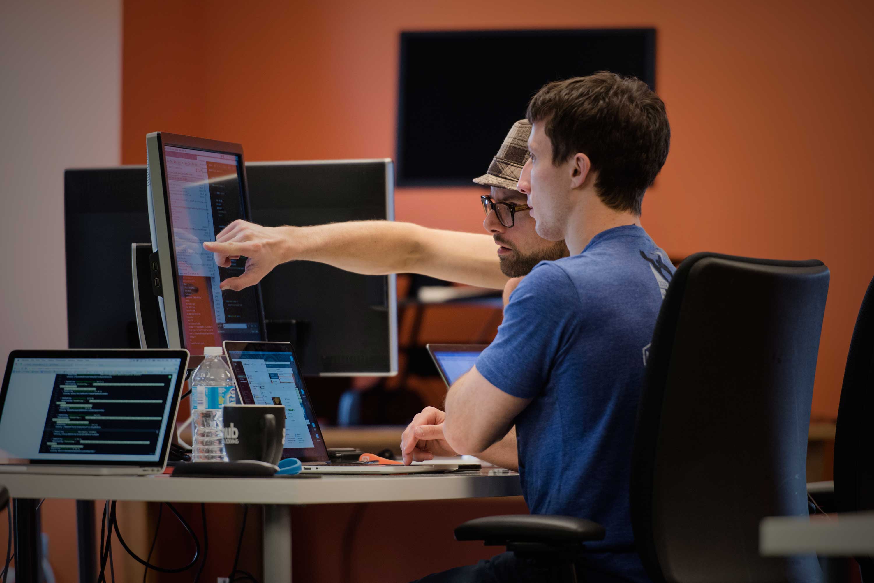 Two Vehikl developers pairing at a workstation